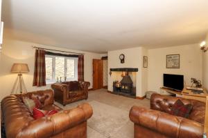 a living room with leather furniture and a fireplace at Howes Beck Cottage in Bampton