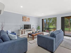 un salon avec deux canapés bleus et une table dans l'établissement Horizons Getaway at the Bay, à Salamander Bay