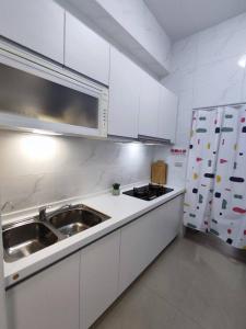 a white kitchen with a sink and a refrigerator at 花蓮Cozy Inn舒適窩民宿 in Hualien City