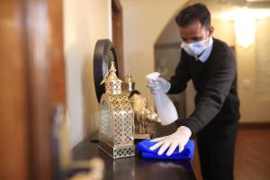 Lamrin Boutique Cottages, Rishikesh في ريشيكيش: رجل بقناع وقفازات يقوم بتنظيف طاولة بها فانوس