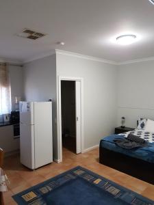 Zimmer mit einem Kühlschrank und einem Bett. in der Unterkunft Rhodeside Lodge in Geraldton