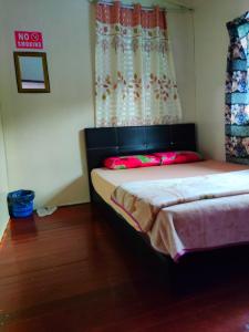a bedroom with a bed and a window with a curtain at Kinabalu Valley Guesthouse in Kundasang