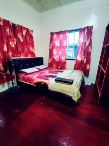 a bedroom with a bed with red drapes at Kinabalu Valley Guesthouse in Kampong Kundassan