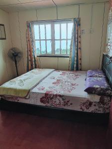 a bed in a room with a window at Kinabalu Valley Guesthouse in Kundasang