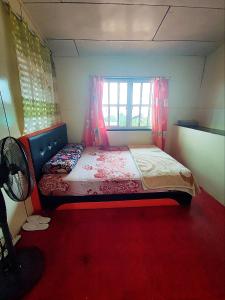 een kleine slaapkamer met een bed en een raam bij Kinabalu Valley Guesthouse in Kampong Kundassan