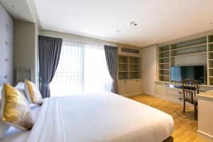 a bedroom with a large white bed with a window at Thea, Executive Suite Serviced Apartment in Ekamai in Bangkok