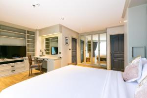 a bedroom with a bed and a desk and a television at Thea, Executive Suite Serviced Apartment in Ekamai in Bangkok
