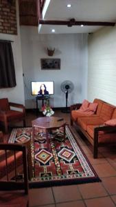 a living room with a couch and a table and a tv at Simbamwenni Lodge and Camping in Morogoro