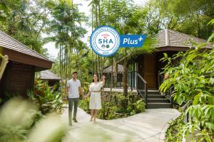 een man en een vrouw staan voor een gebouw bij River Kwai Resotel in Sai Yok