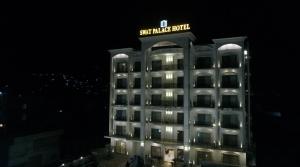 a building with a sign on top of it at night at Swat Palace Hotel By Northin in Mām Derai