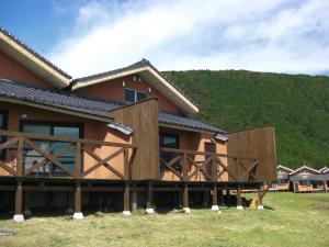 a house with a large deck with a mountain in the background at Resonate Club Kuju in Taketa
