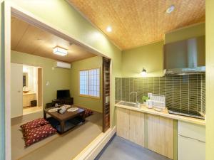 uma cozinha com paredes verdes e uma mesa num quarto em 宿家千の森 em Tóquio