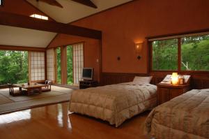 a bedroom with two beds and a tv and windows at Resonate Club Kuju in Taketa