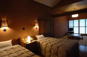 um quarto de hotel com duas camas e duas lâmpadas em Resonate Club Kuju em Taketa