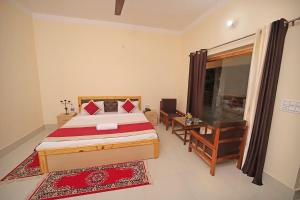 a bedroom with a bed and a desk and a window at FabHotel Corbett Green View Garden and Stay in Rāmnagar