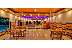 a restaurant with wooden tables and chairs and purple lights at FabHotel Corbett Green View Garden and Stay in Rāmnagar