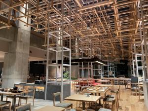 un restaurante con mesas de madera, sillas y techos en AMANEK Beppu YULAｰRE en Beppu