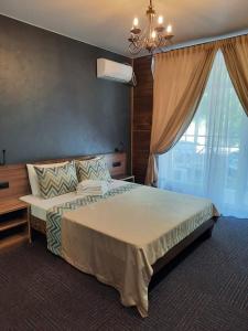 een slaapkamer met een groot bed met een kroonluchter en een raam bij Апартаменты в ГЛК Солнечная долина in Syrostan