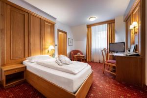 ein Hotelzimmer mit einem Bett und einem Schreibtisch mit einem Computer in der Unterkunft VILA VITA Burghotel Dinklage in Dinklage