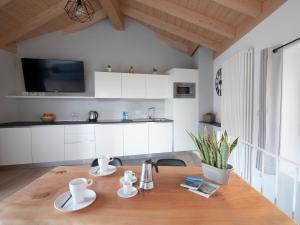 cocina con armarios blancos y mesa de madera en Bellano Holidays - Casa Artemio en Bellano