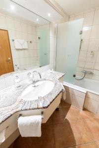 ein Badezimmer mit Waschbecken, Dusche und Badewanne in der Unterkunft VILA VITA Burghotel Dinklage in Dinklage