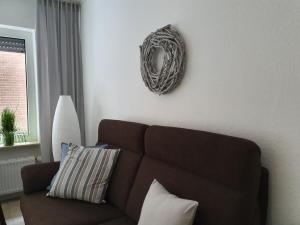 a living room with a brown couch and a wreath on the wall at Mila am Meer in Neuharlingersiel