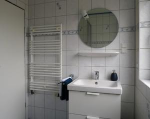a white bathroom with a sink and a mirror at Mila am Meer in Neuharlingersiel