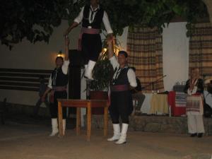 un grupo de personas de pie delante de una persona de pie en una mesa en Ellinospito, en Axós