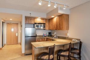 a kitchen with wooden cabinets and a stainless steel refrigerator at Grand Lodge 1-Bedroom Condo with 3 Queens & Close to Everything condo in Crested Butte