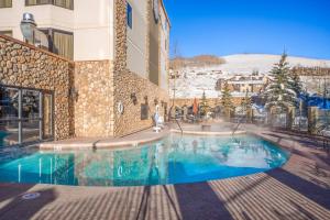 a swimming pool in front of a building with snow at Grand Lodge 1-Bedroom Condo with 3 Queens & Close to Everything condo in Crested Butte