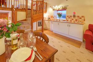 a kitchen and living room with a wooden table and chairs at Rose Cottages in Alnwick