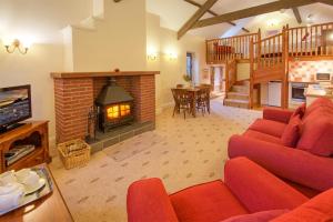 a living room with a red couch and a fireplace at Rose Cottages in Alnwick