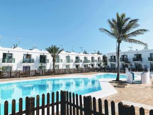 basen przed budynkiem z palmą w obiekcie Sinfonia Corralejo iRent Fuerteventura w Corralejo