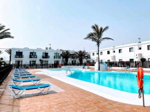 basen z leżakami obok budynku w obiekcie Sinfonia Corralejo iRent Fuerteventura w Corralejo
