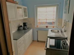 a kitchen with white cabinets and a sink and a window at Ferienwohnung Kahlenberg in Thale