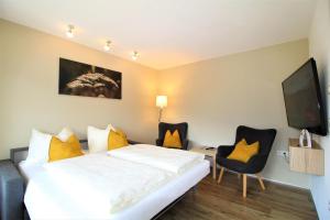 a hotel room with a bed and chairs and a tv at Appartements Cilli in Neukirchen am Großvenediger