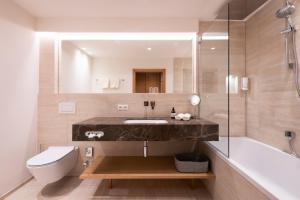 een badkamer met een wastafel, een bad en een toilet bij Hotel Garni Edelweiss in Lech am Arlberg