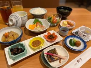 una mesa de madera con platos de comida. en Hotel Tetora en Hakodate