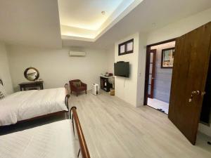 1 dormitorio con 1 cama, TV y puerta en Rose Garden, en Hualien City