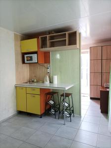a kitchen with yellow and green cabinets and a table at House&House 84 in Petropavlovskaya Borshchagovka