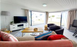 sala de estar con sofá y TV en Orca Cottage, en St Helena Bay