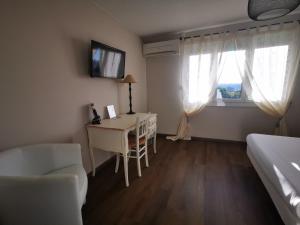 Schlafzimmer mit einem Schreibtisch, einem Bett und einem Fenster in der Unterkunft Le Mas des Quintrands Manosque - Motel de charme in Manosque