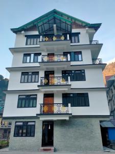 a tall white building with balconies on it at KhenKhim Regency, Lachen all meals included in Lachen