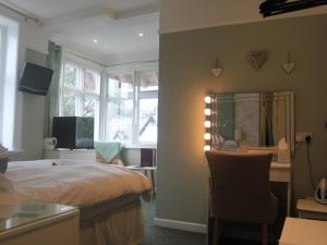 um quarto com uma cama e uma secretária com um espelho em The Red House Guest House em Falmouth