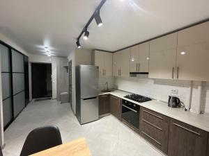 a kitchen with wooden cabinets and a stainless steel refrigerator at Стильна квартира в новому будинку, поряд центр та р. Дніпро in Cherkasy