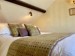 Un dormitorio con una cama con almohadas. en Rose Cottages, en Alnwick
