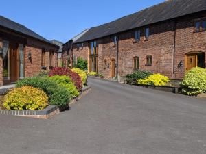 an empty road between brick buildings with colorful plants at North Mere Rural Cottages in Kenilworth
