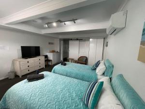 a bedroom with two beds and a couch and a television at Beach & Bay Holiday Rental - Nelson Bay in Nelson Bay
