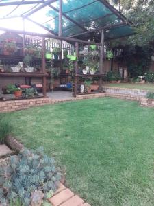 a garden with a wooden pergola and a lawn at Stunning BnB in Gorgeous Garden Setting in Germiston