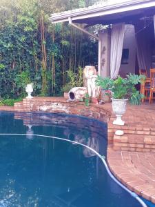 a swimming pool next to a house with a patio at Stunning BnB in Gorgeous Garden Setting in Germiston